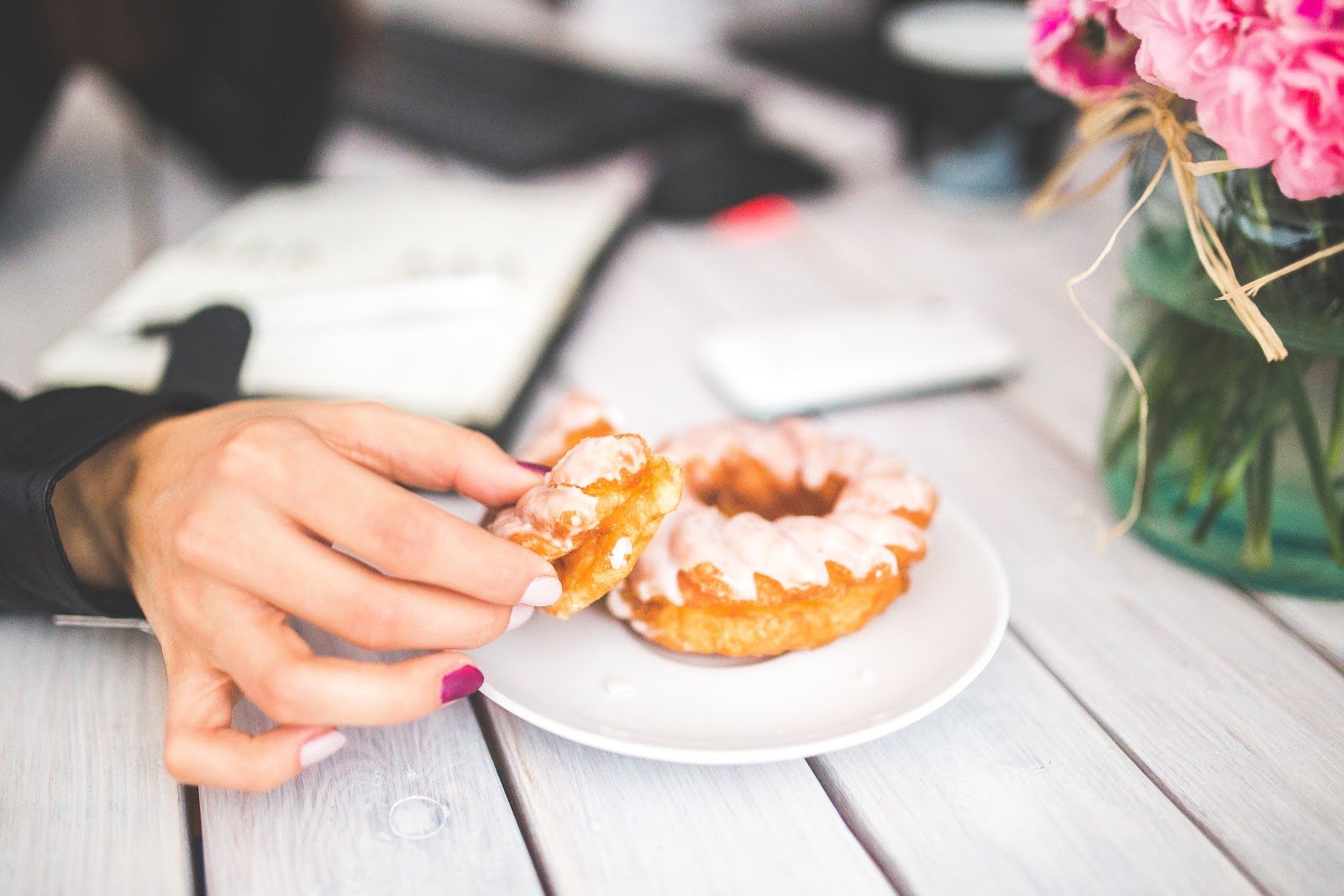 womans-hand-with-painted-nails-holding-frosted-donuts