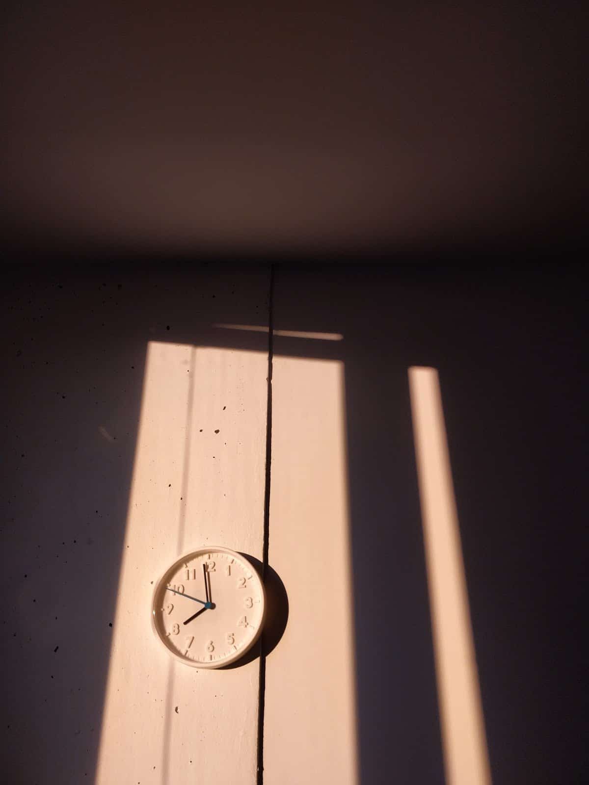 white-clock-on-white-wall-with-heavy-shadows