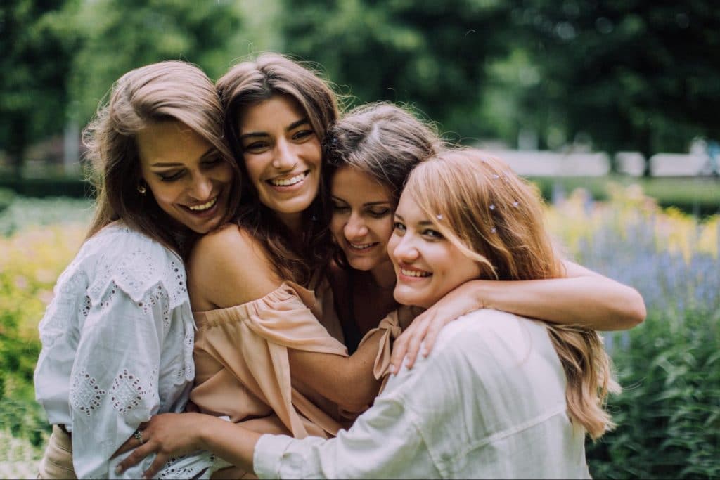 Four healthy young women group hug.