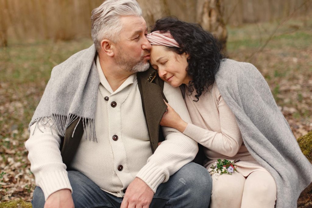 older couple being affectionate with one another in a park i the fall