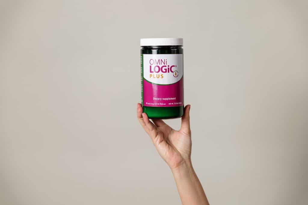 A bottle of Omni Logic Plus prebiotics being held up by hand. Omni Logic Plus is a prebiotic supplement.