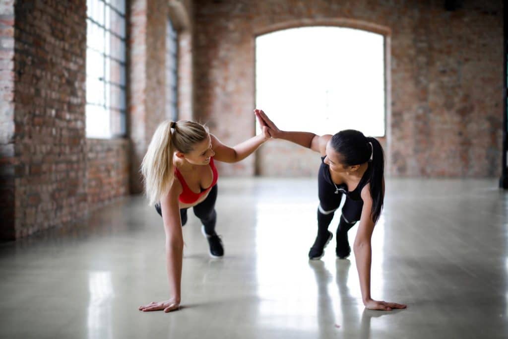 Two athletes high five as they stretch. Having a good balance of probiotics supported by prebiotics along with regular exercise can help support a healthy gut.