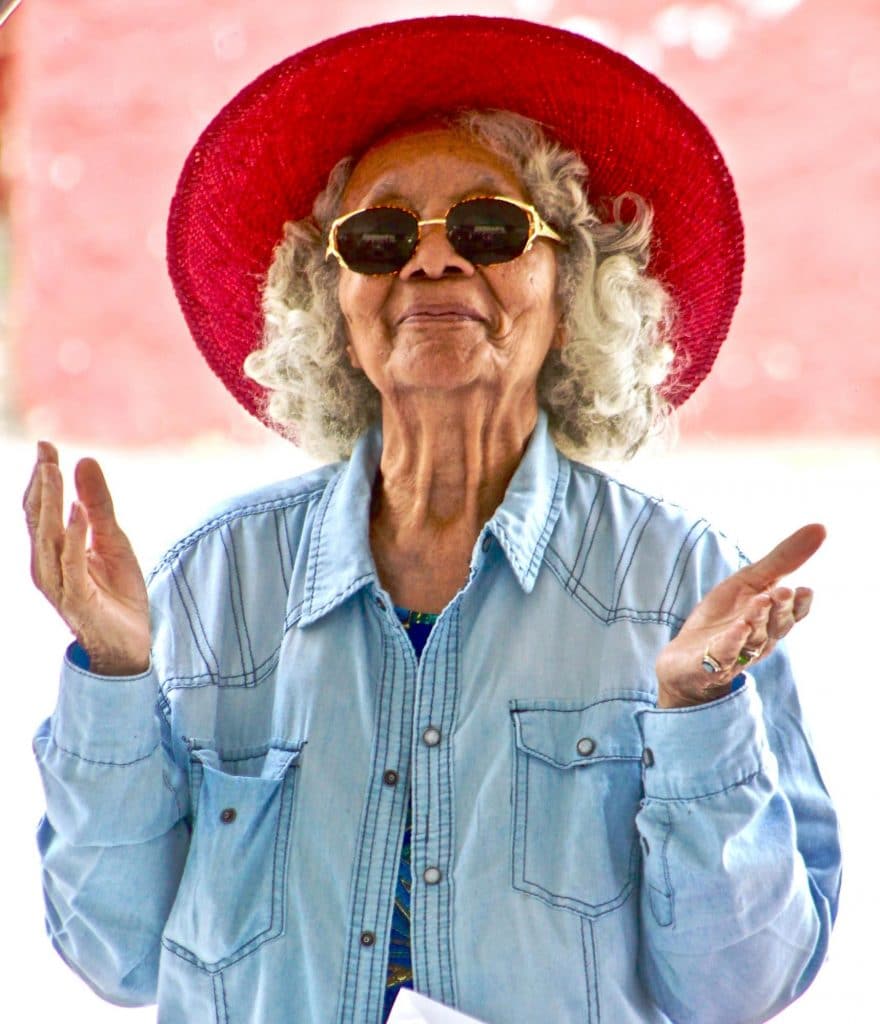 senior woman in red hat holding her hands up in a peaceful pose