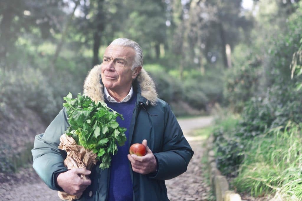 senior man walking down country lane carrying fresh groceries