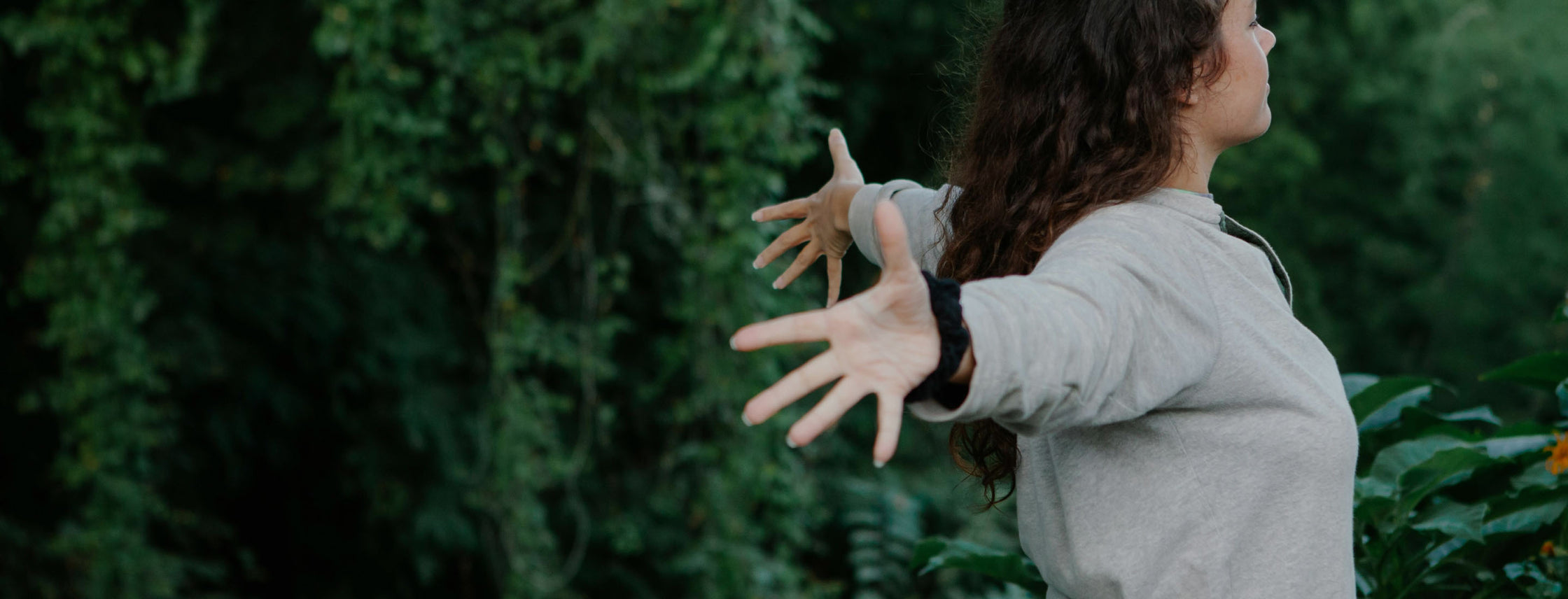 The image shows a woman in a field, reaching out with her hands towards the sky, symbolizing immune support and the desire to boost immunity, manage allergies and skin conditions, and rebalance gut flora