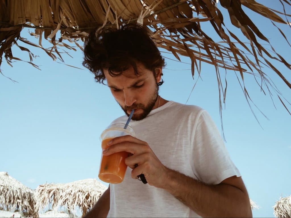 man drinking cold beverage on beach