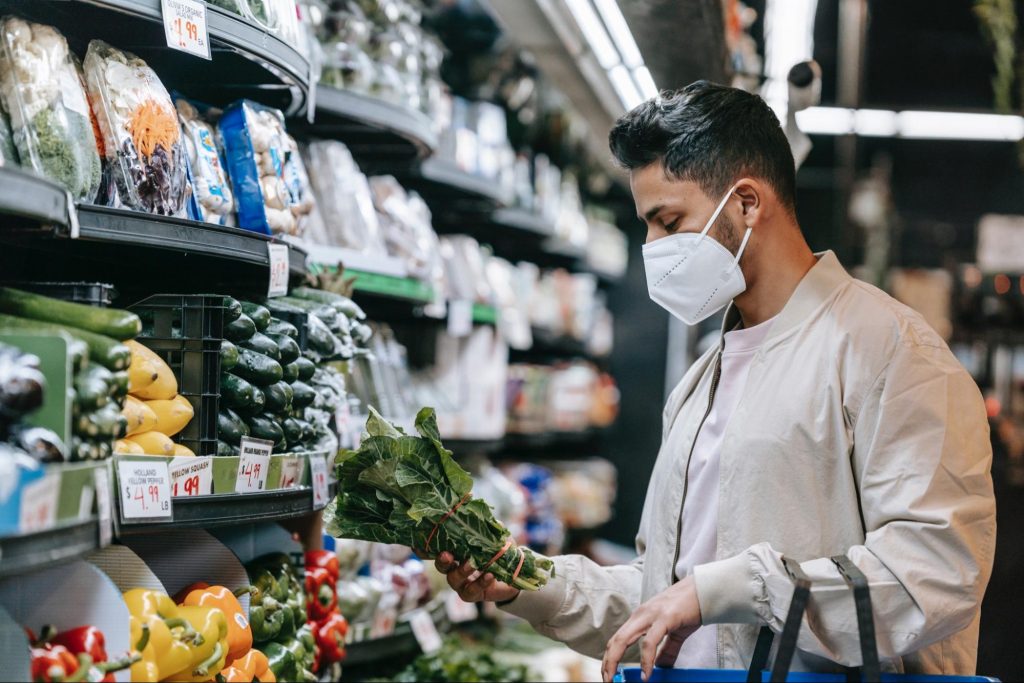 Man in grocery store looking at vegtables.