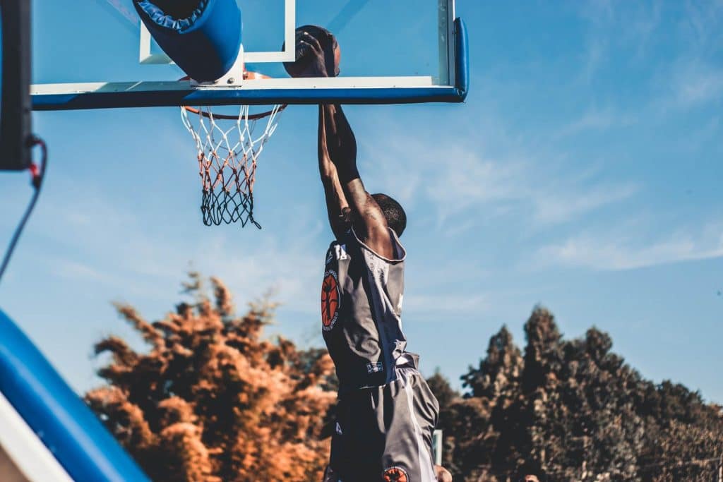 A healthy man does a slam dunk while playing basketball. Proper nutrition and a balanced gut with prebiotics and probiotics can help people with an active and healthy lifestyle.