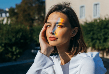 woman-sitting-in-plaza-with-light-prism-on-face