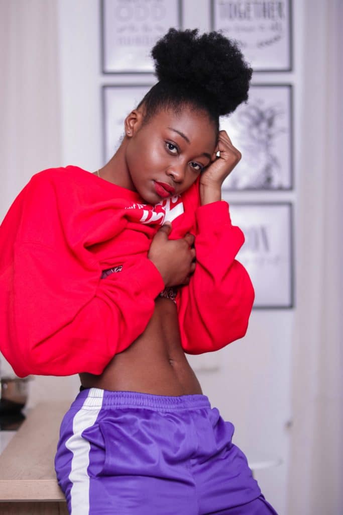 woman in a red sweatshirt and purple shorts showing abs