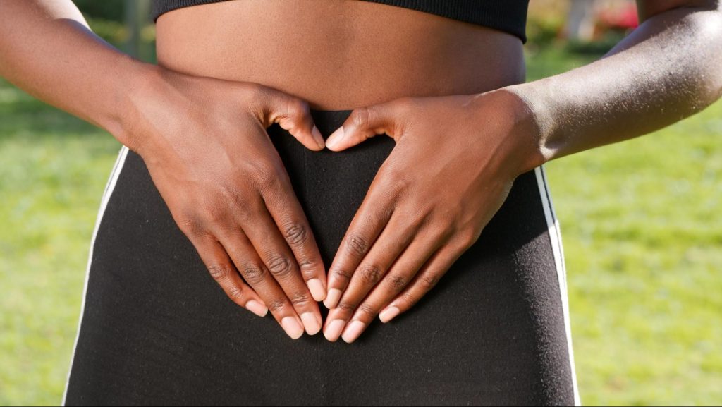 Woman in exercise clothes presses hands to belly.