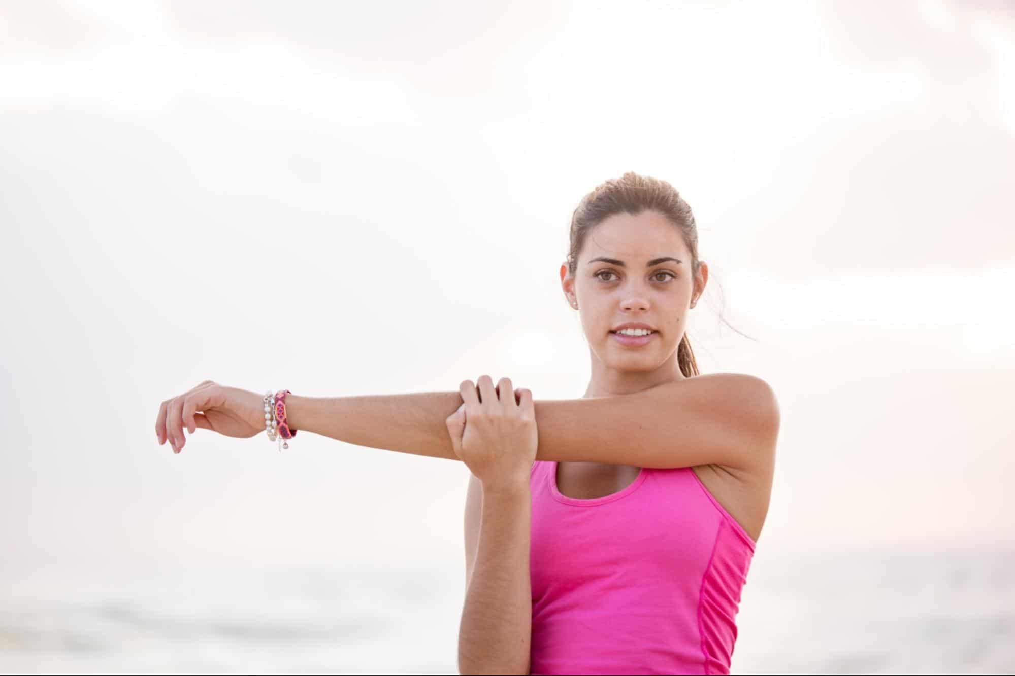 Woman in pink shirt stretching before exercise.