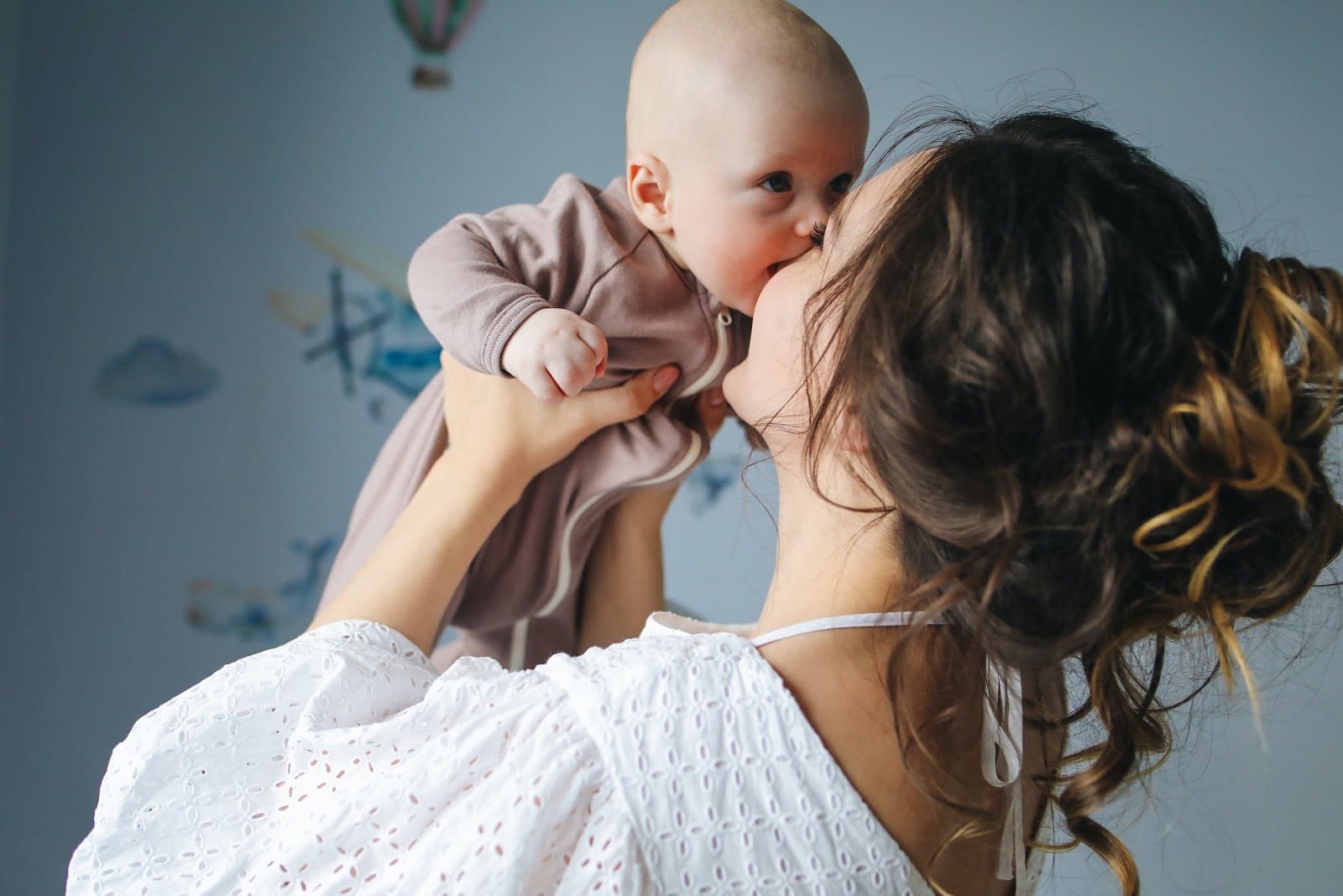 woman-in-white-top-carrying-baby-in-brown-onesie